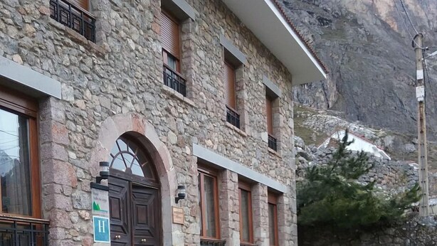 Un edificio de piedra con una puerta de madera, escalones que conducen a la entrada y una mesa de picnic al frente.
