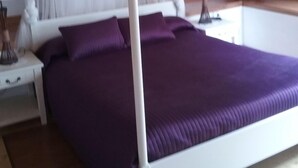 Una cama con dosel, una mesita de noche y otra mesilla.