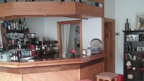 Zona de bar con taburetes de madera, una barra con utensilios y un espejo.