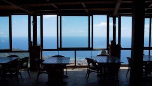 Un comedor con mesas y sillas, ventanas amplias y vista al mar.