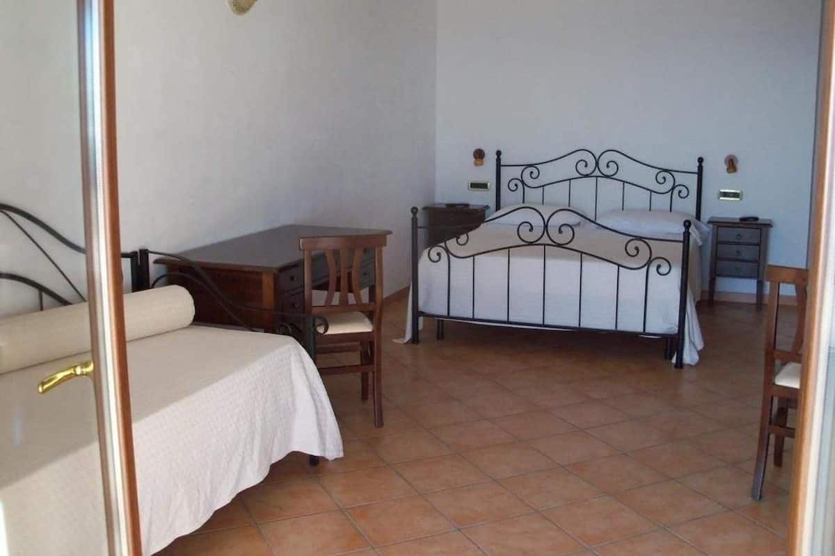 A bedroom with a bed, a desk, and a chair.