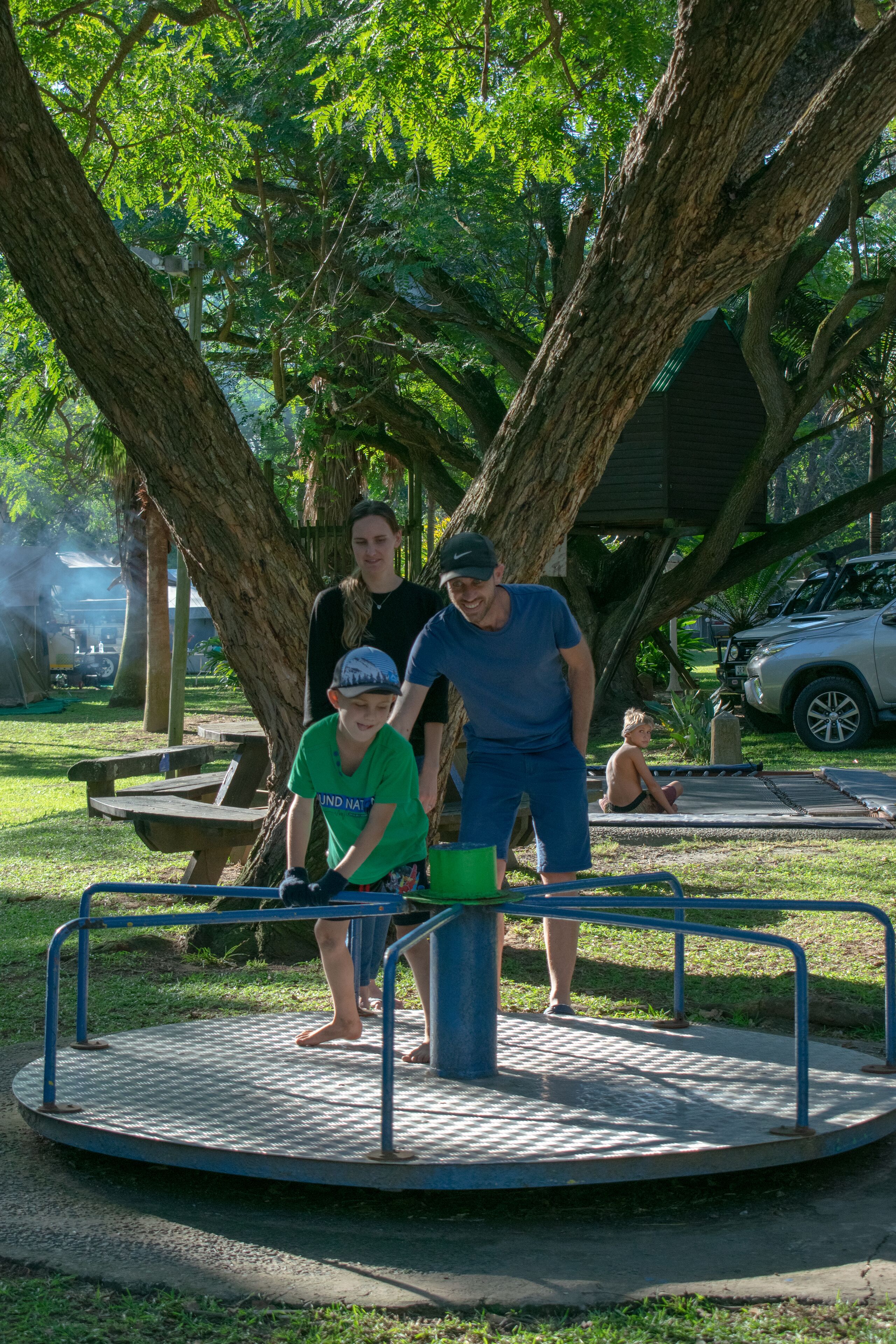 Un espacio circular para sentarse al aire libre con barandillas metálicas, rodeado de árboles y una mesa de picnic.