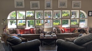 Un salon confortable avec une grande fenêtre, un canapé et deux fauteuils.
