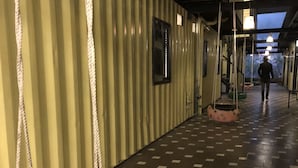 A corridor with a checkered floor, a swing with a colorful tire seat, and a person walking in the distance. - Homestay Discovery Sapa (Sa Pa)
