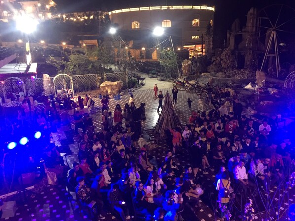 A crowded outdoor area with a stage and a large audience.