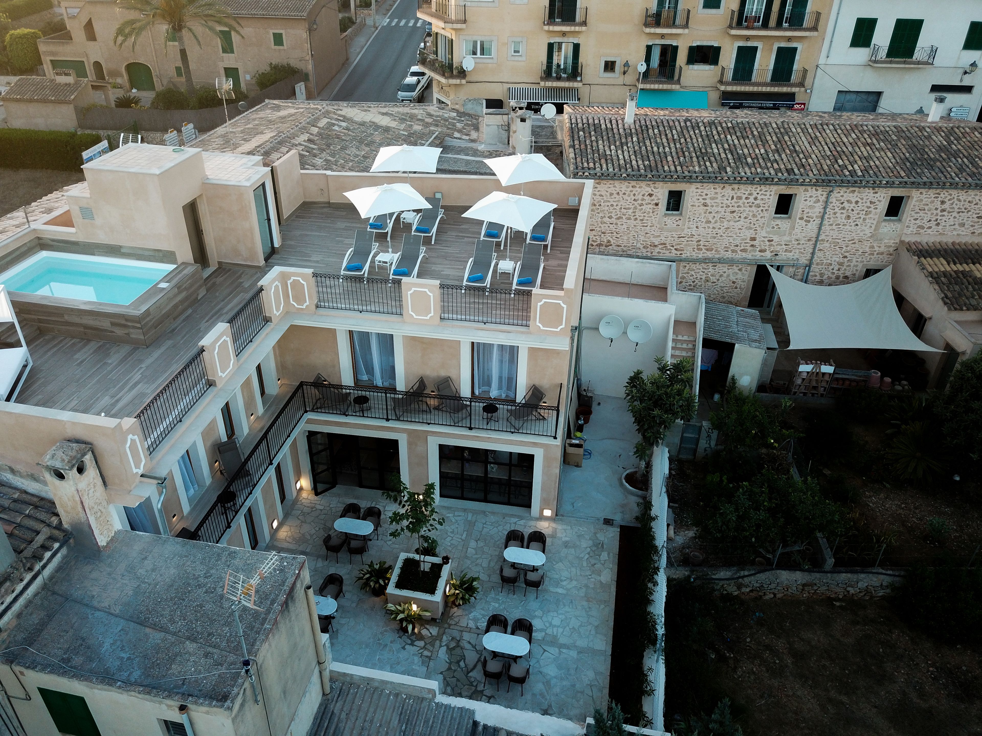 Un edificio de varios pisos con piscina en la azotea, zona de estar al aire libre y varios balcones.