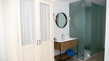 Un baño con tocador blanco, un espejo y cabina de ducha de vidrio.