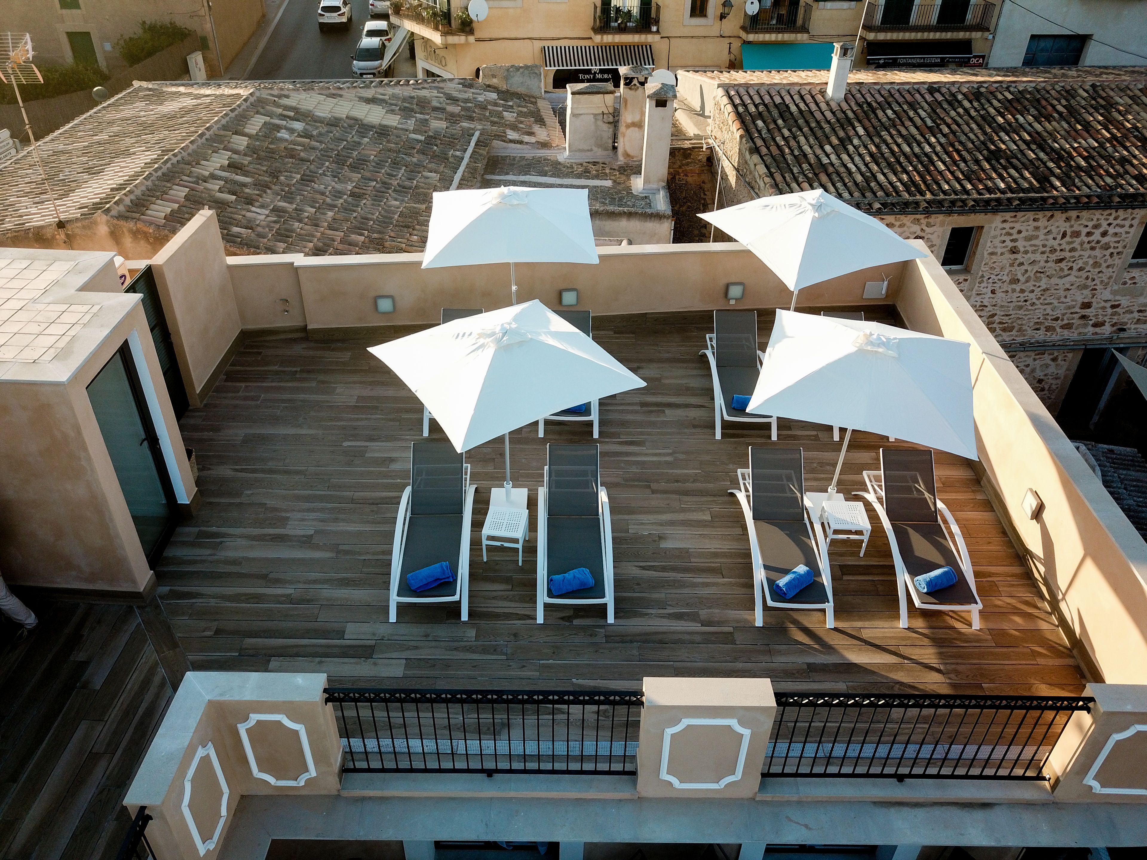 A rooftop terrace with white umbrellas, lounge chairs, and a wooden deck.