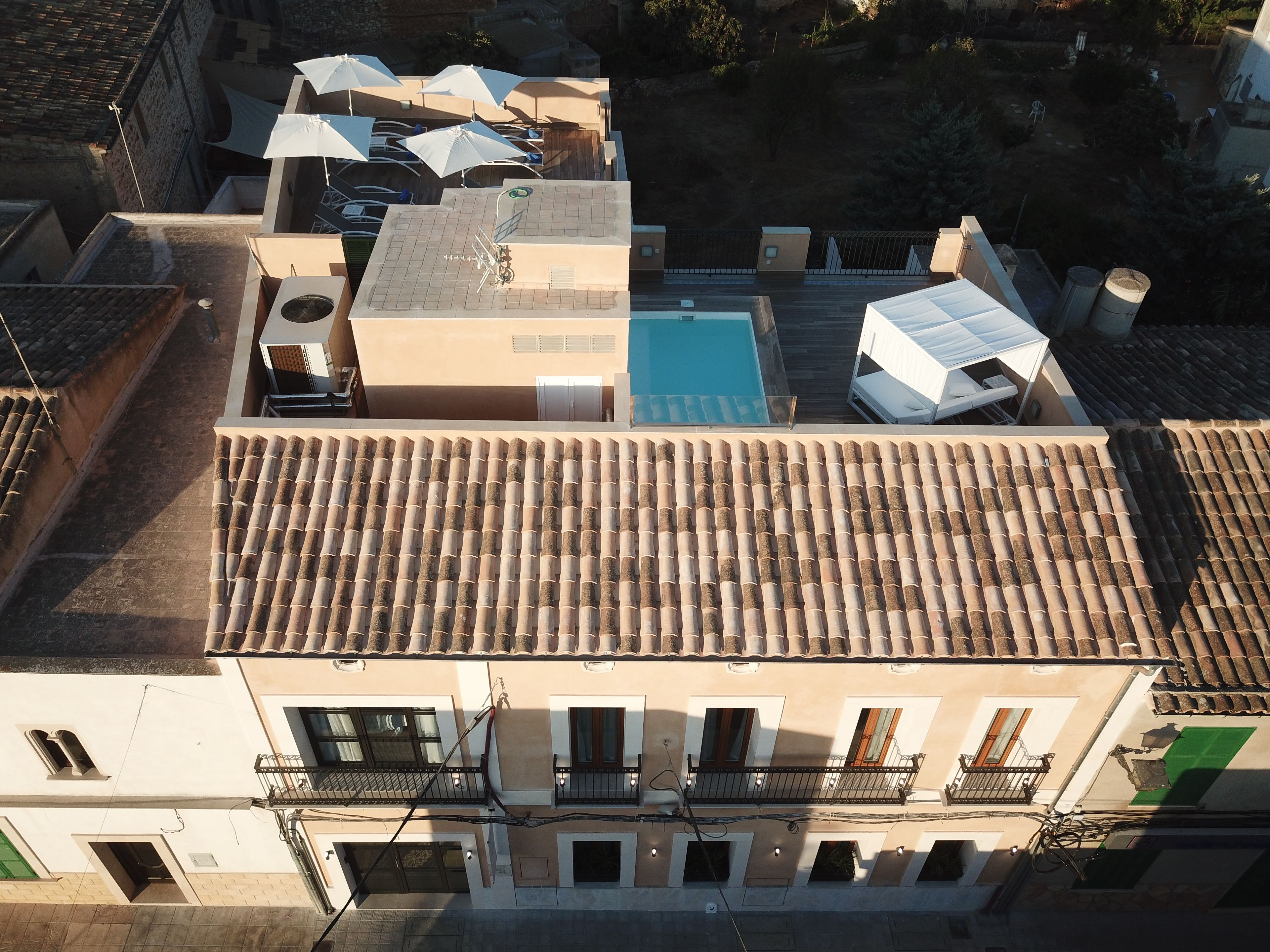 Una terraza con piscina, varios paraguas y tejado de baldosas.