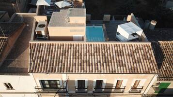 Una terraza con piscina, varios paraguas y tejado de baldosas.