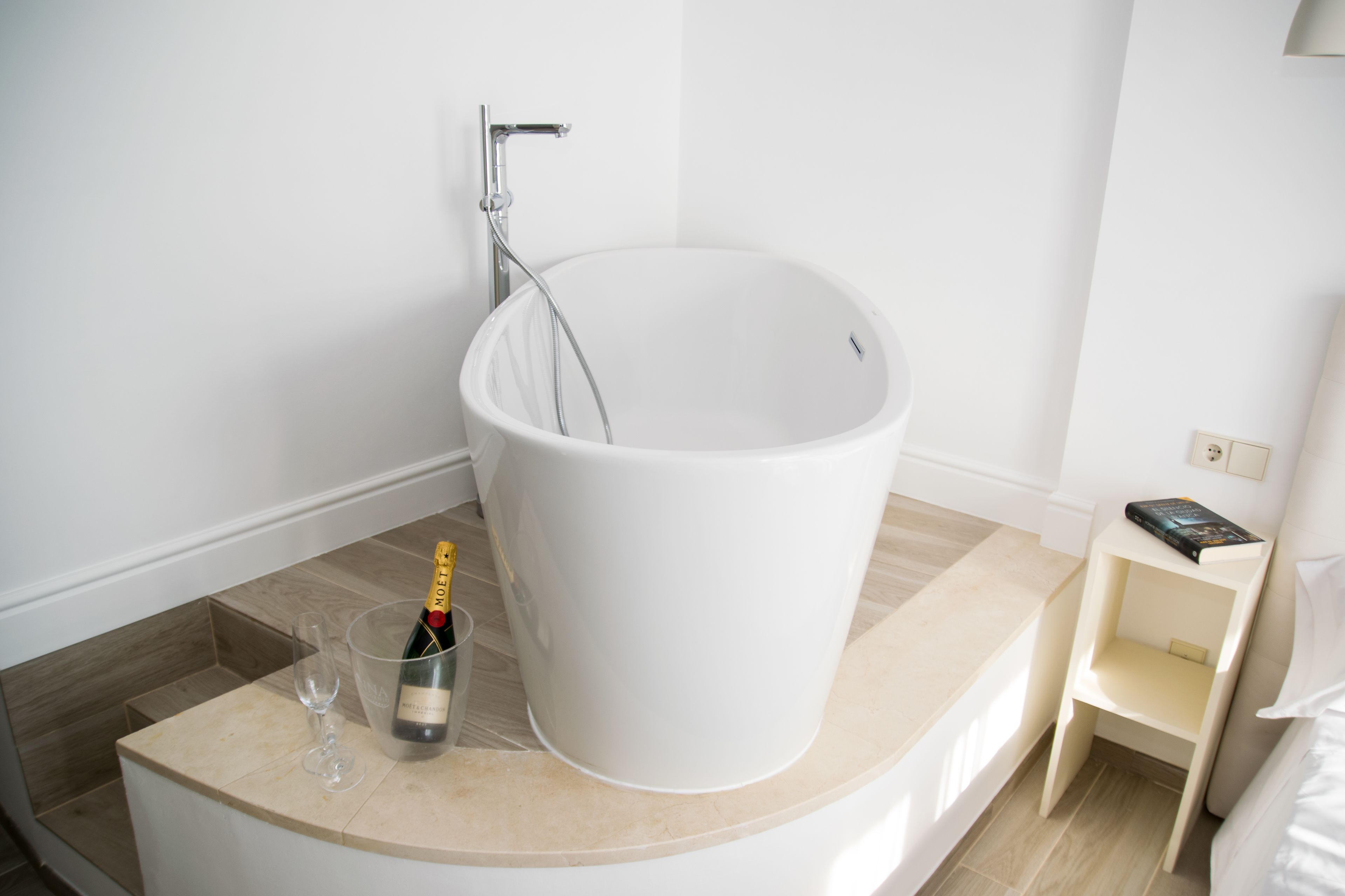 Un baño moderno con una bañera grande, una copa de vino y una botella de champán.