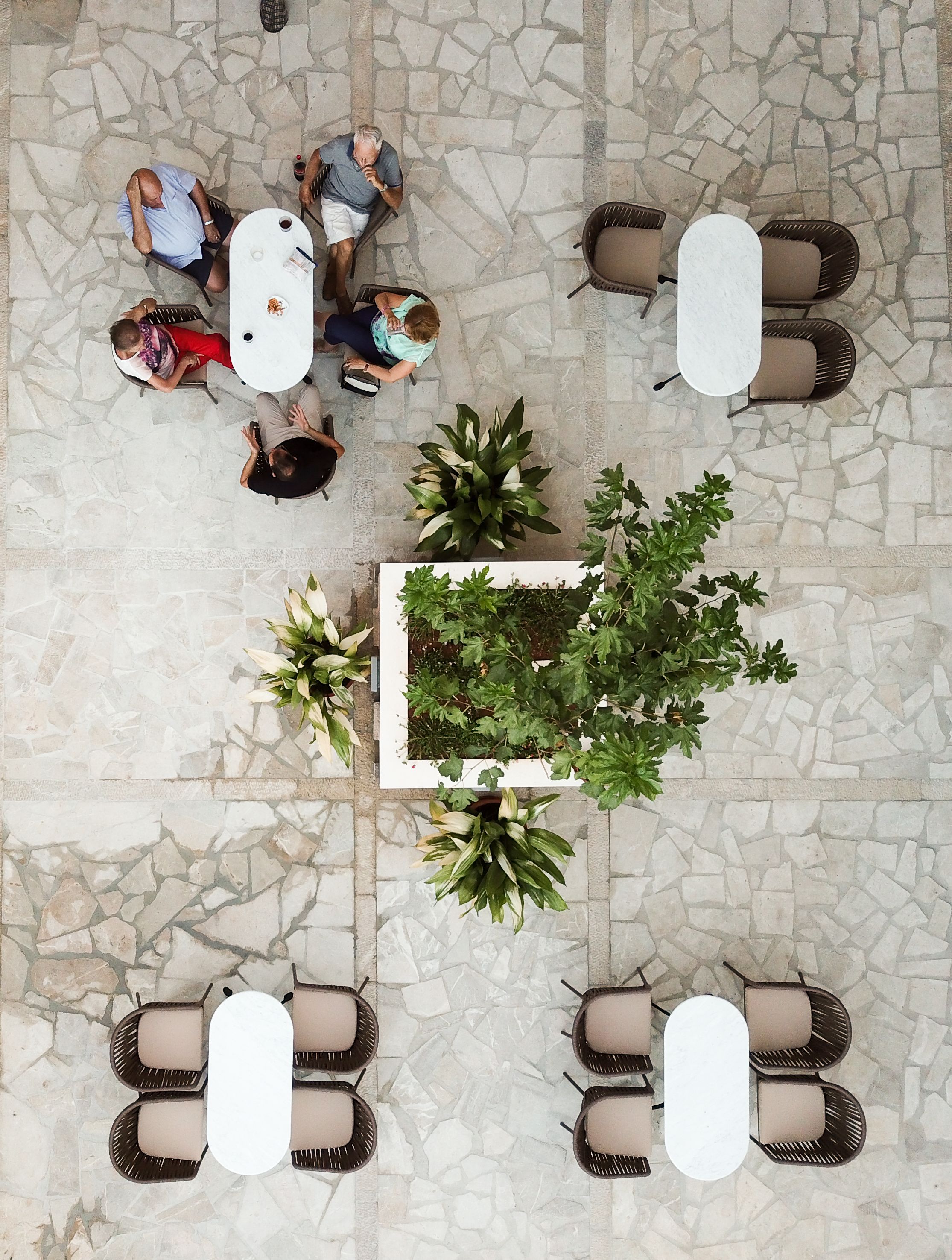 A top-down view of a patio area with stone flooring, surrounded by tables and chairs.