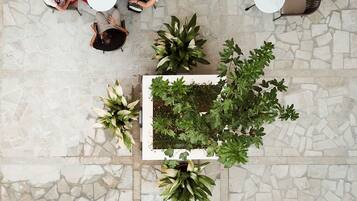 A top-down view of a patio area with stone flooring, surrounded by tables and chairs.