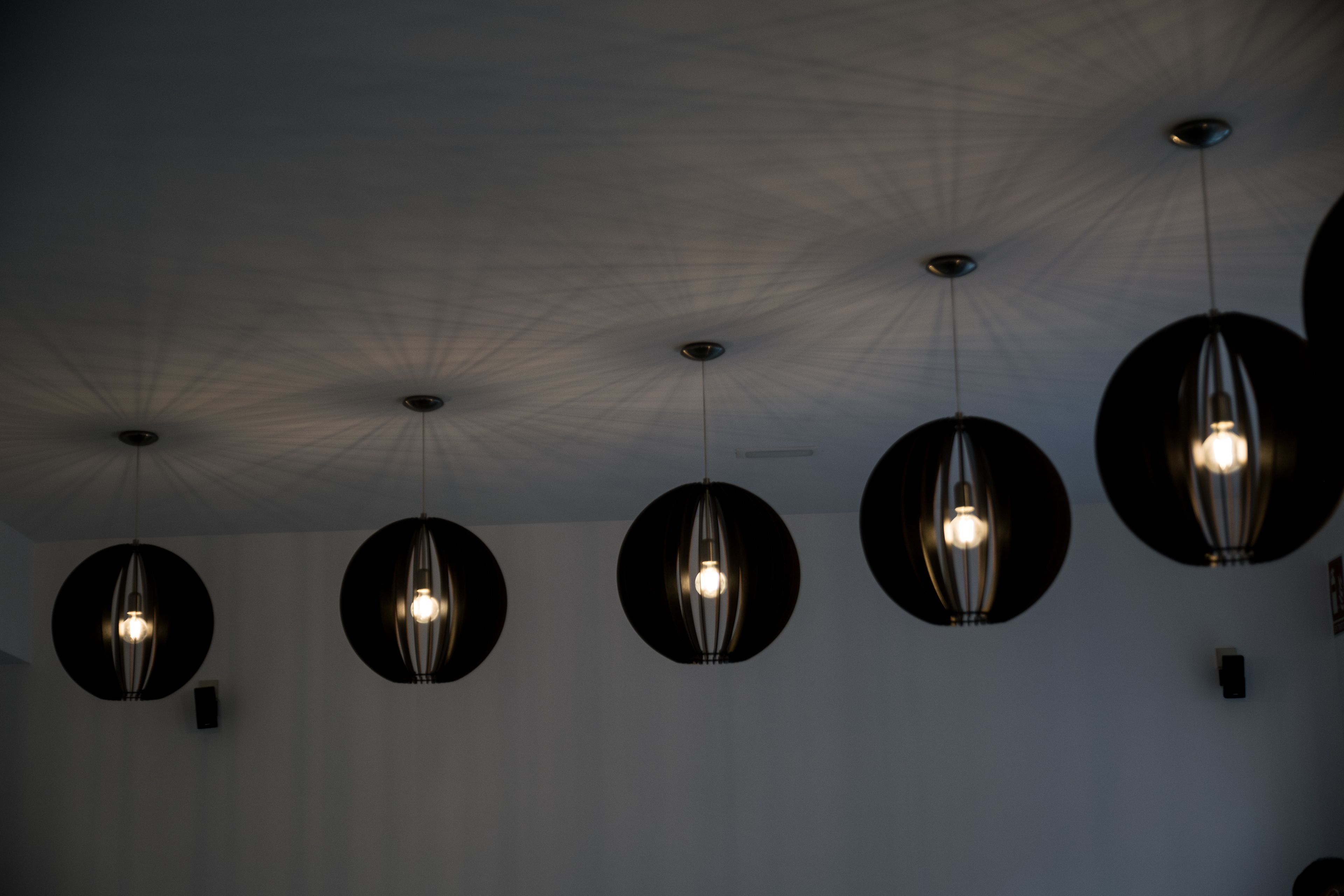 A ceiling with five spherical pendant lights.