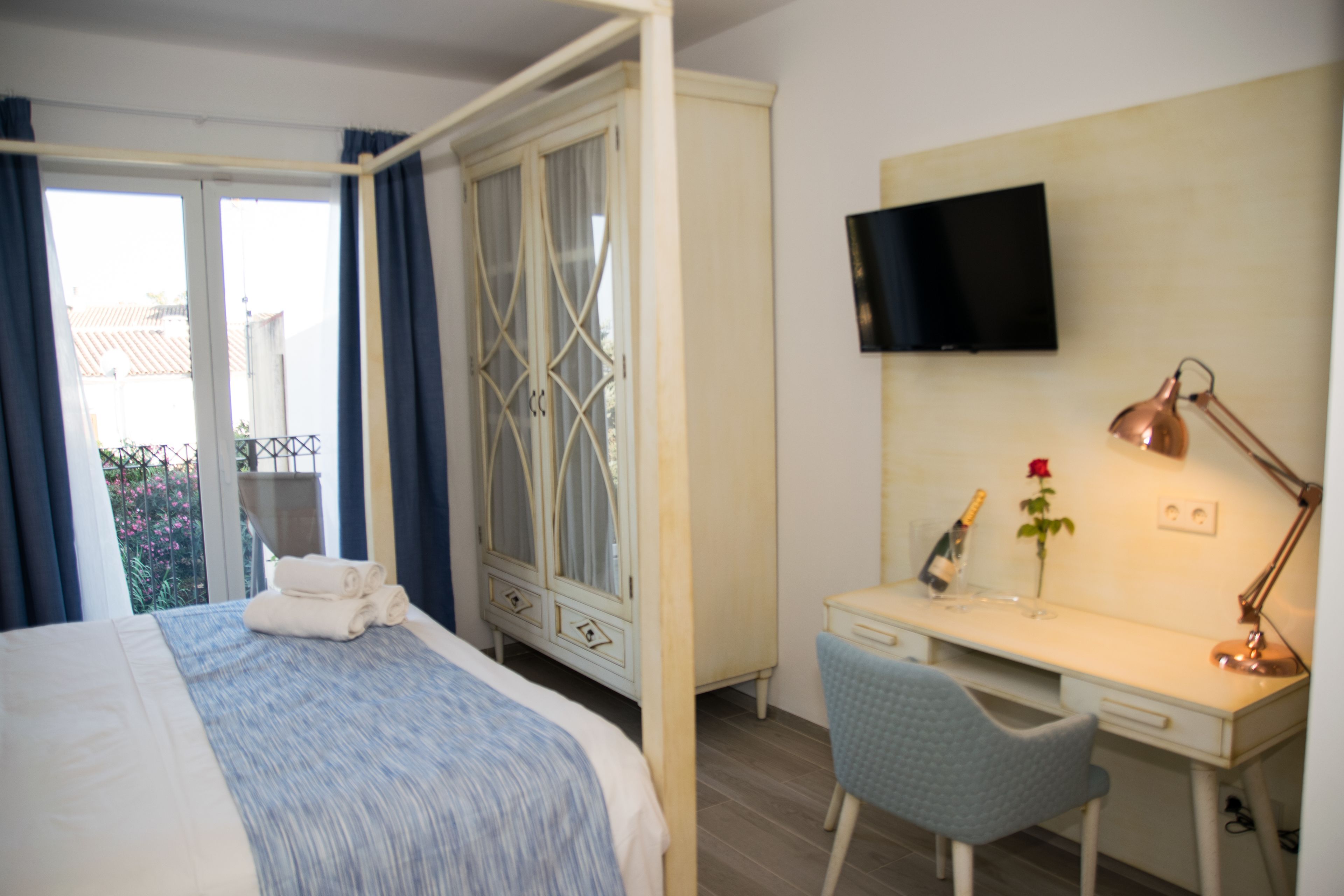 A bedroom with a bed, a desk, a chair, a TV, and a wardrobe.