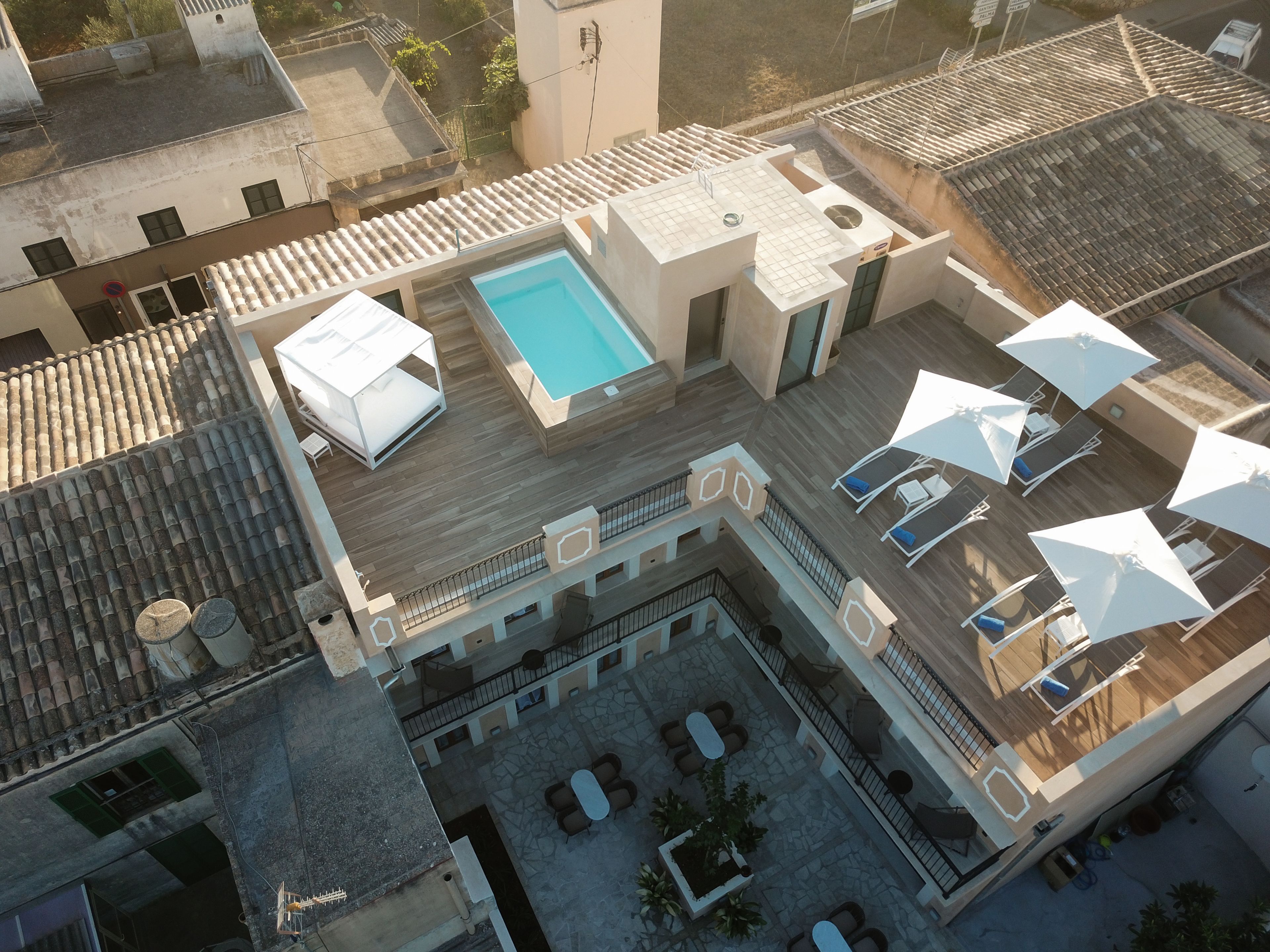 An aerial view of a rooftop with a swimming pool, outdoor seating, and a covered area with umbrellas.