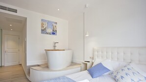 A modern hotel room with a large bed, a built-in bathtub, and a painting on the wall. - Petit Hotel Sant Miquel - Adults Only (Santanyi)