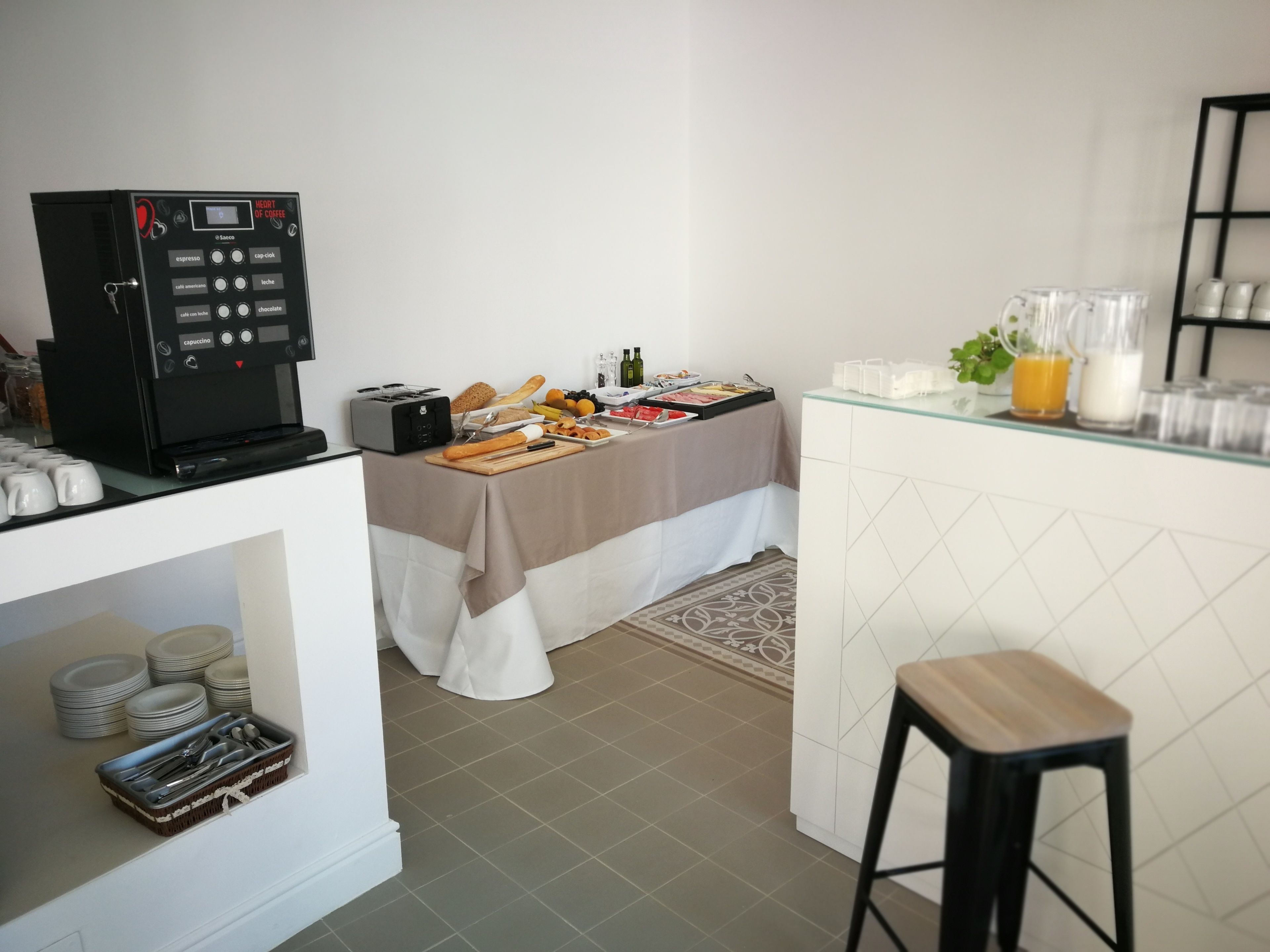 Una kitchenette equipada con cafetera, tostadora y una barra de desayuno con diversos alimentos y bebidas.