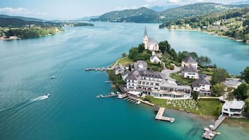Luftaufnahme eines Seeanwesens mit einer Kirche, mehreren Gebäuden und angestoßenen Booten.