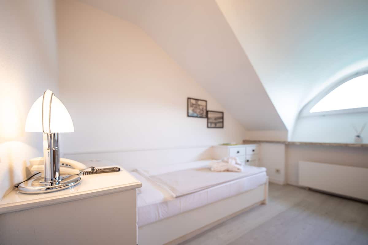 Ein Schlafzimmer mit einem Bett, einem Nachttisch mit Lampe und einem kleinen Beistelltisch.