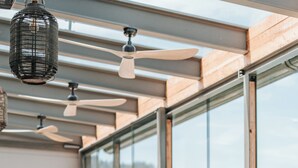 A restaurant with wooden tables and chairs, large windows, and ceiling fans. - Hotel Linde (Maria Woerth)