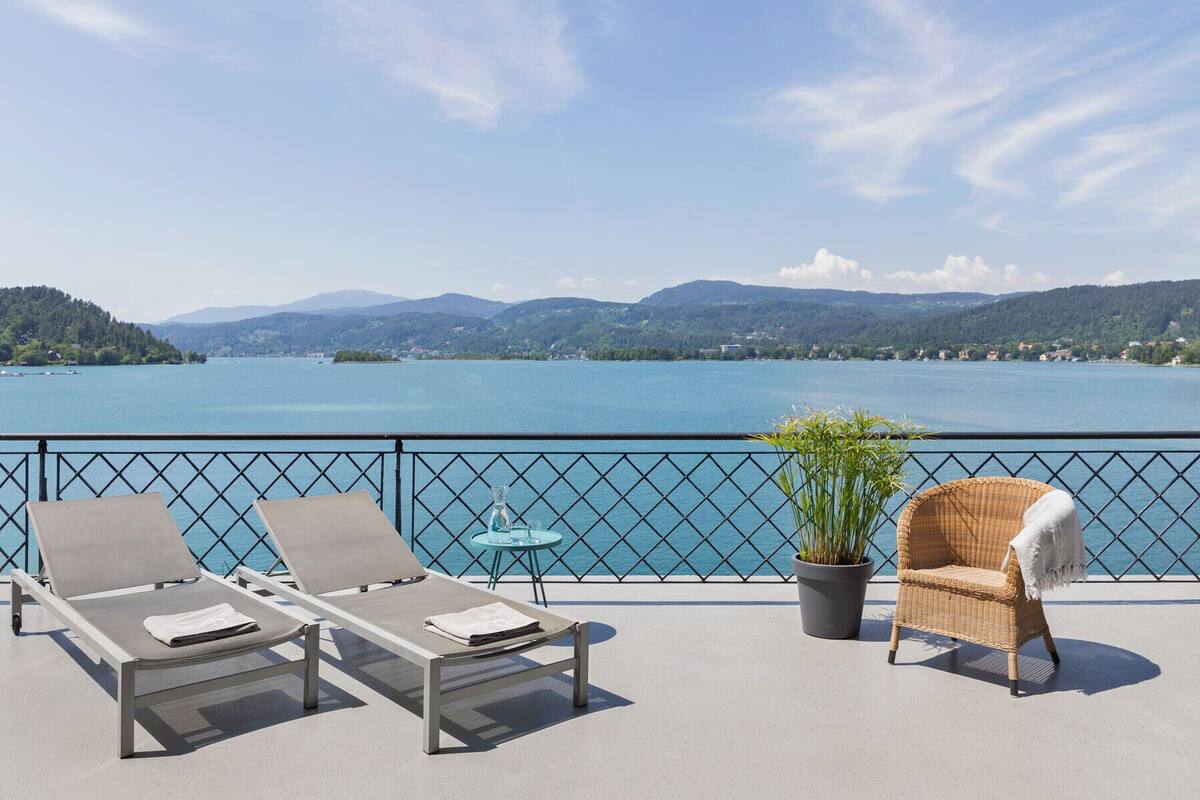 Ein Balkon mit zwei Liegestühlen, einem kleinen Tisch und einem Blumentopf.