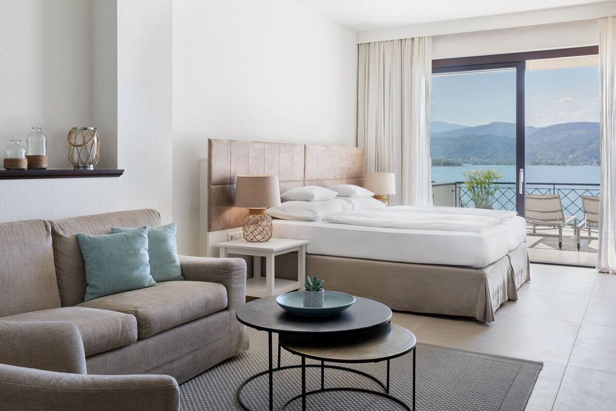 Ein Hotelzimmer mit Bett, Sofa, kleinem Tisch und einem Balkon mit Bergblick.