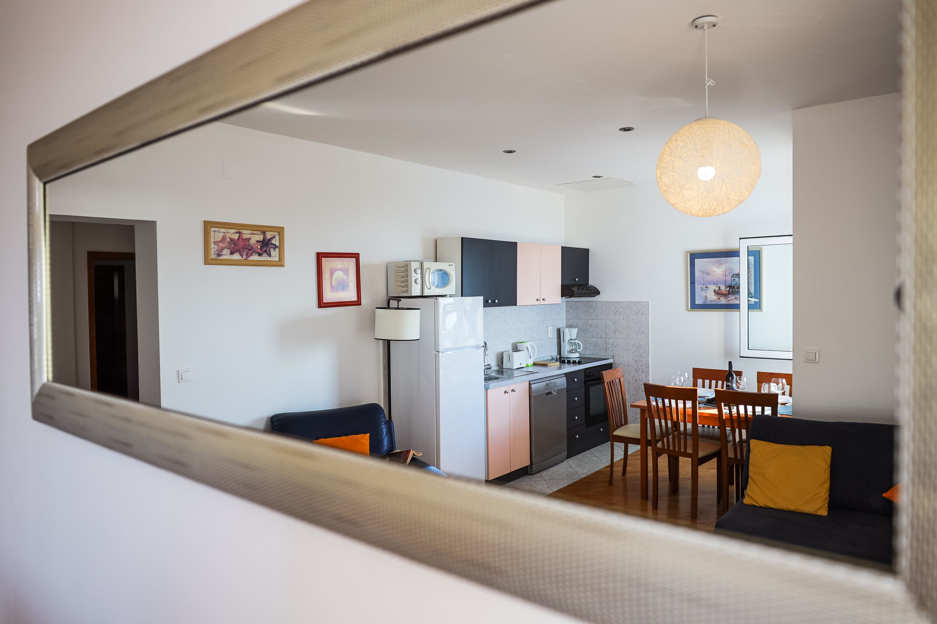 Ett modernt kök med matplats, en soffa och en hängande lampa.