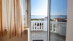 Een balkon met uitzicht op zee en gebouwen.