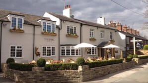 A traditional pub named "The Dog Free House" with outdoor seating and stone walls. - The Dog at Peover (Knutsford)