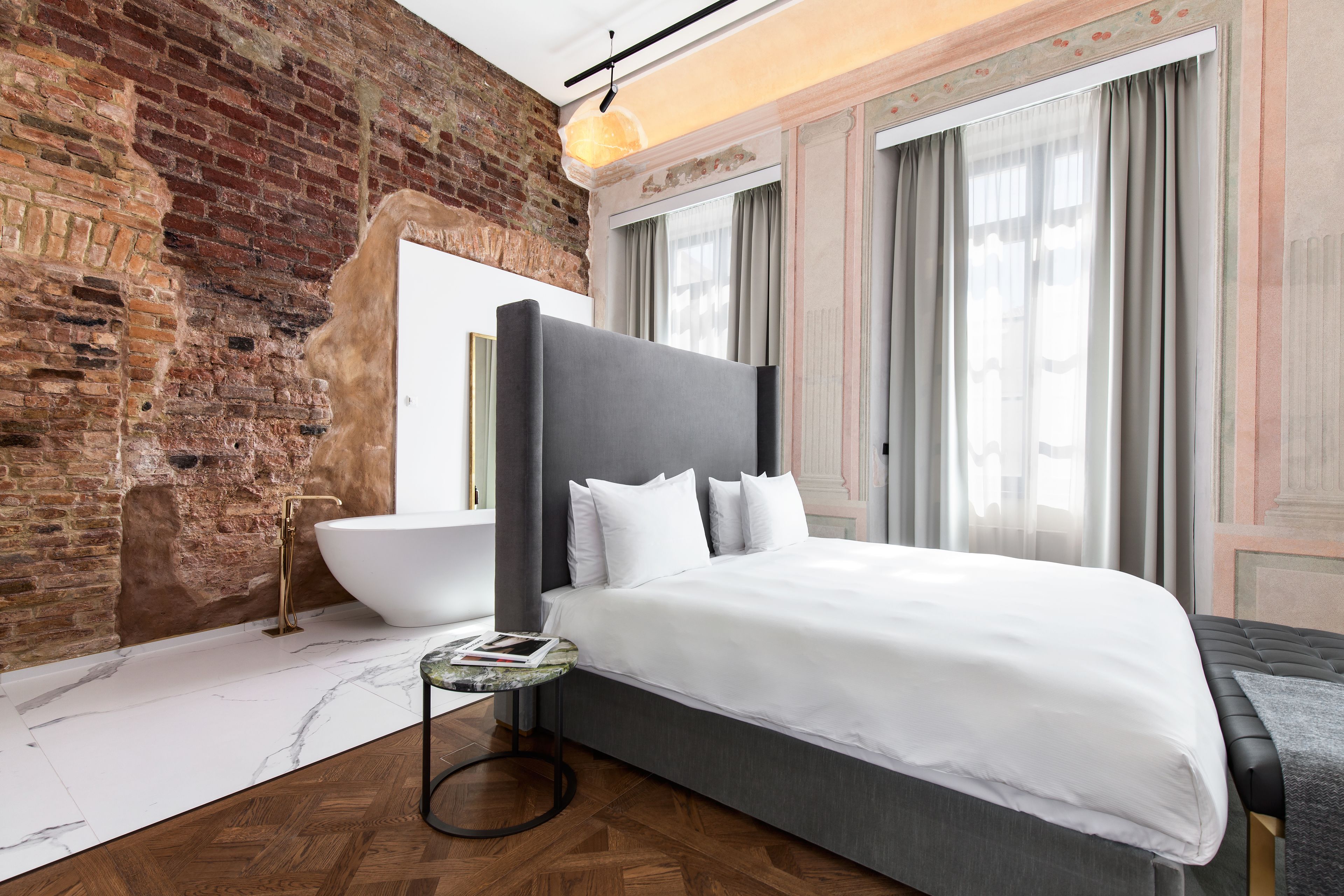 Un dormitorio moderno con una cama grande, una bañera blanca y una pared de ladrillo.