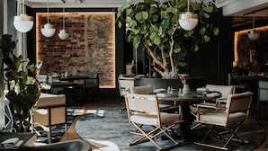 A modern dining area with a brick wall, hanging plants, and contemporary furniture. - Hotel Pacai, a Member of Design Hotels (Vilnius)