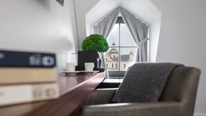 A modern room with a view of a historic building through a large window with white curtains.