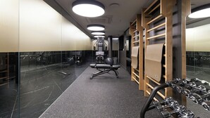 A modern gym with exercise equipment, mirrored walls, and a clean, polished floor.