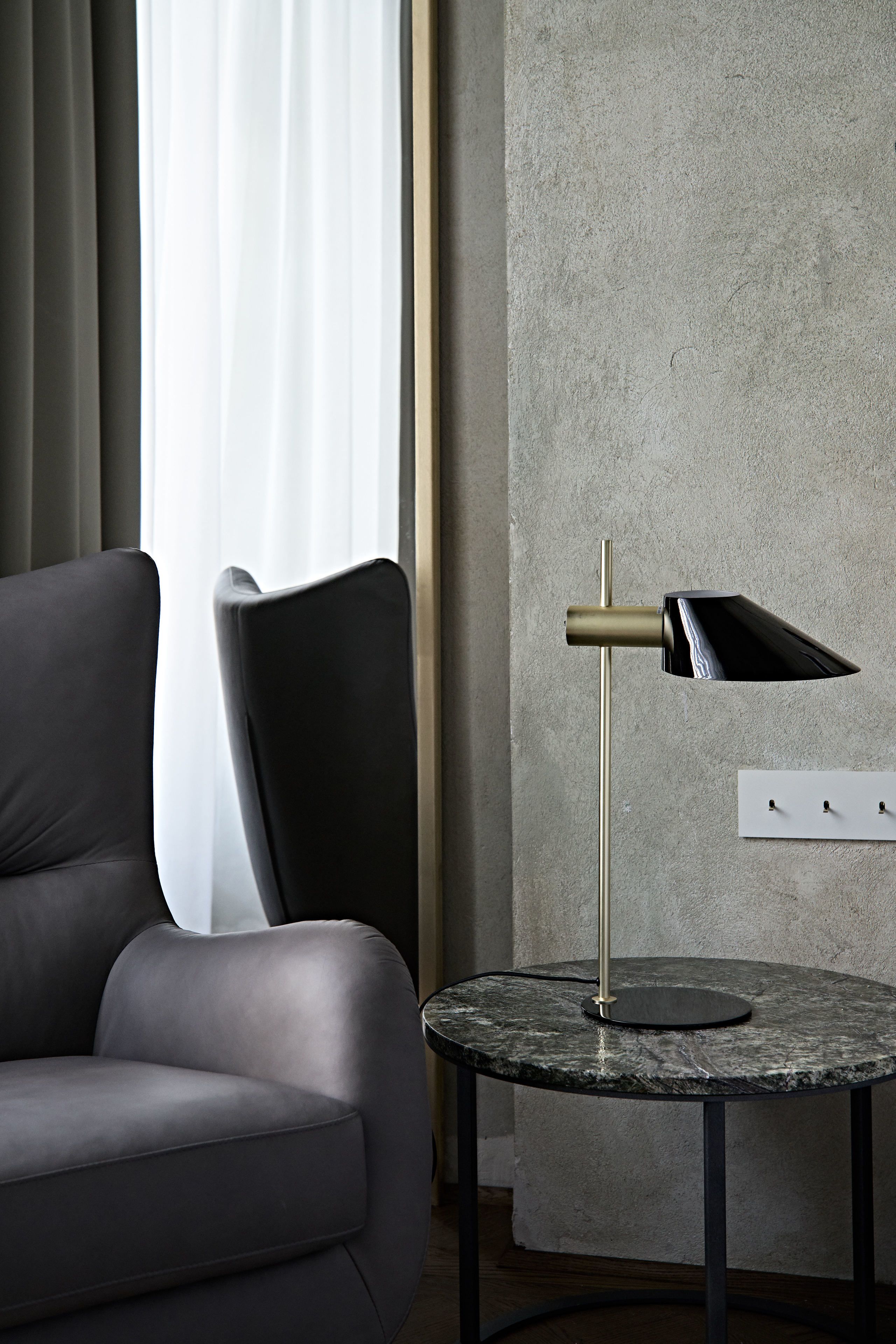 A modern room with a round marble table, a black and gold floor lamp, and a grey sofa.