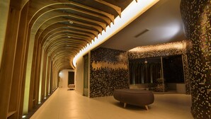 Un interior moderno con techo de madera curvada, pared con diseño y una zona de estar.