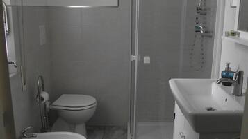 A bathroom with a toilet, bidet, and a shower enclosure.