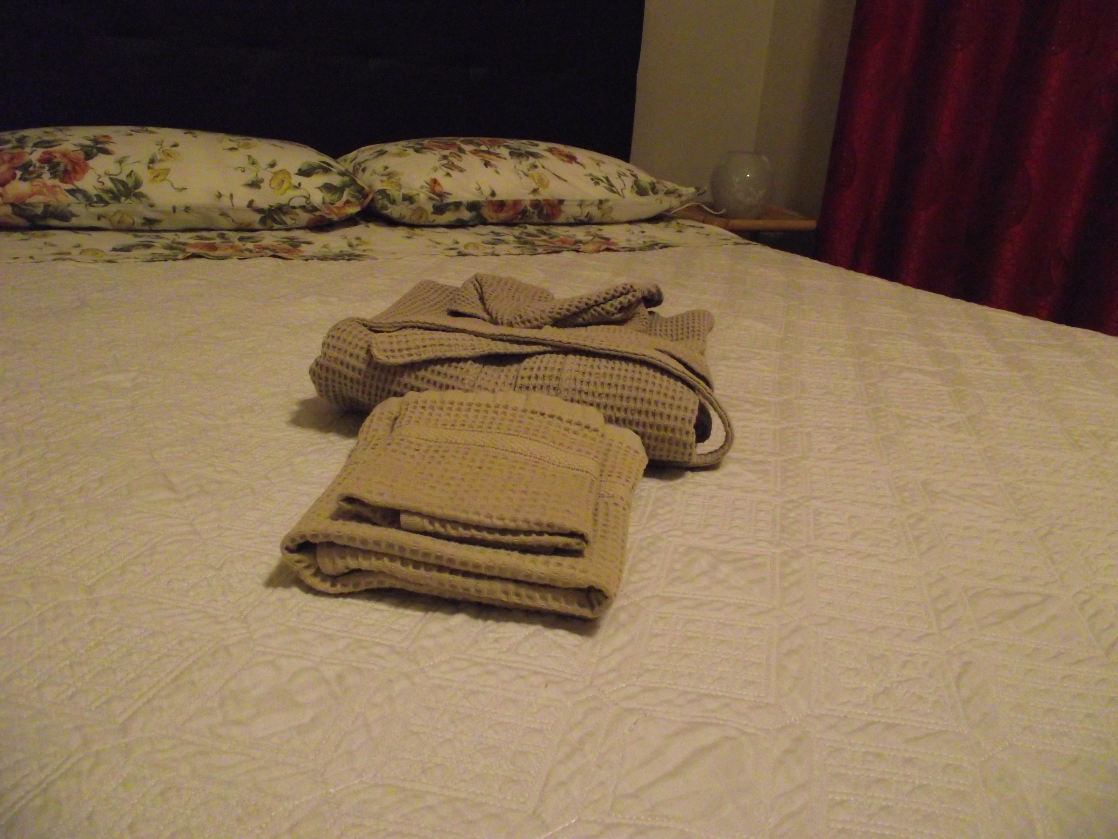 A neatly made bed with a floral-patterned pillow and a folded blanket.
