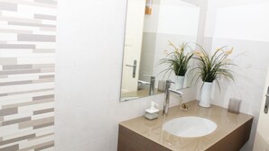 A modern bathroom with a large mirror, a sink, and two potted plants.