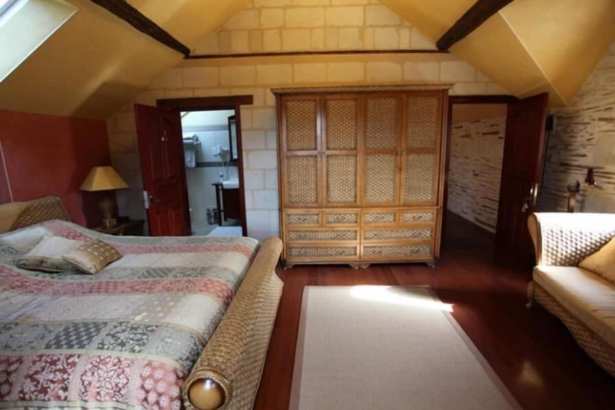 A bedroom with a large bed, a wooden wardrobe, and a small sofa.