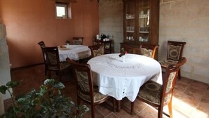 A dining area with a round table, chairs, a chandelier, and a cabinet with glass doors. - Château de Belle Poule  (Les Ponts-de-Ce)