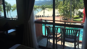 Une chambre avec vue sur une piscine, une plage et des montagnes.