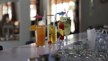 Zona de bar con varios vasos de bebidas diversas, algunas con sombrillas y pajitas.