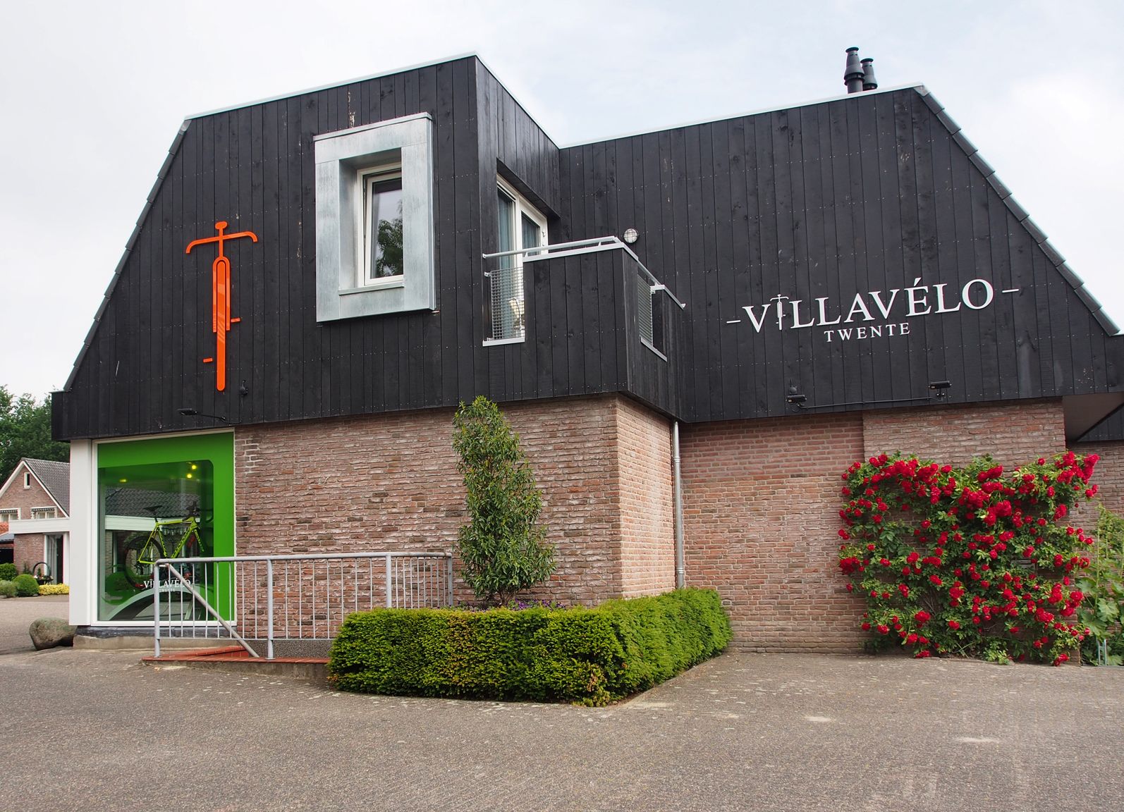 Un edifici amb façana negra, una porta verda i un rètol que diu "VILLAVÉLO TWENTE".