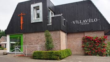 A building with a black exterior, a green door, and a sign reading "VILLAVÉLO TWENTE".