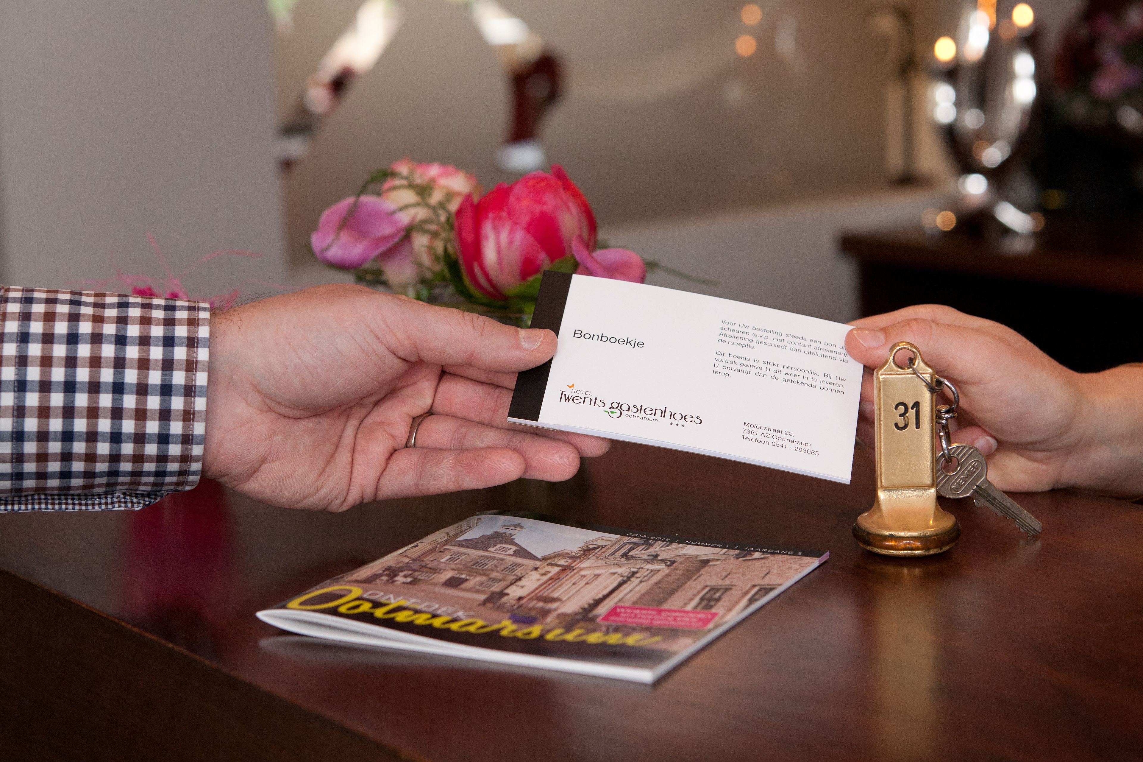 A person handing over a business card and a key to another person.