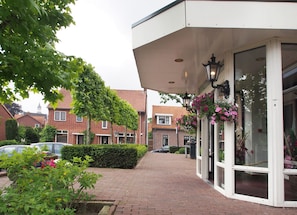 A brick pathway leading to a building with a white facade and large windows. - Villavelo Twente (Ootmarsum)