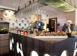 A modern bar area with a tufted wall, a wine rack, and a coffee machine.