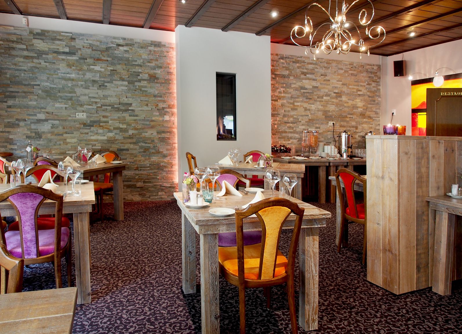 A restaurant interior with stone walls, wooden tables, and chairs.