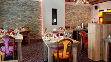 A restaurant interior with stone walls, wooden tables, and chairs.
